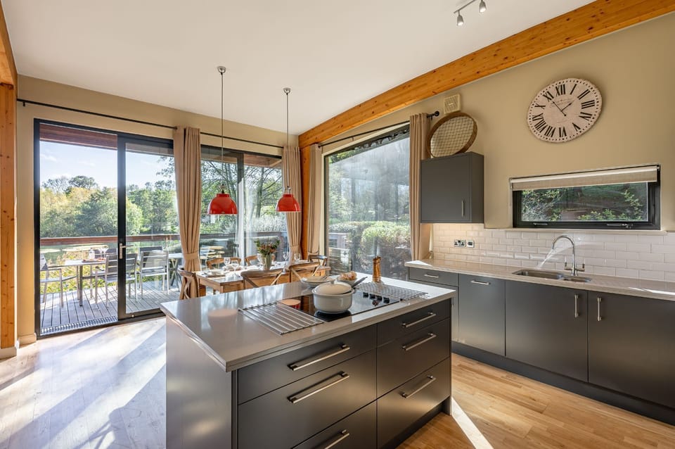Stylish kitchen and dining space at Imogen lodge with large windows, wooden table, and red pendant lights.