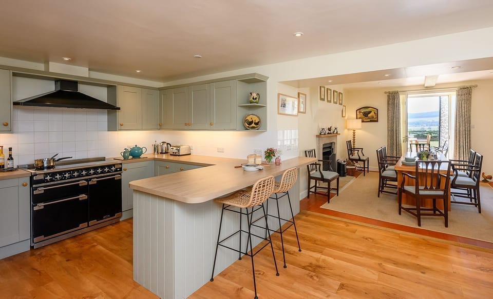 Spacious open-plan kitchen and dining room at Hollins Farmhouse in the Yorkshire Dales with breakfast bar and garden views.