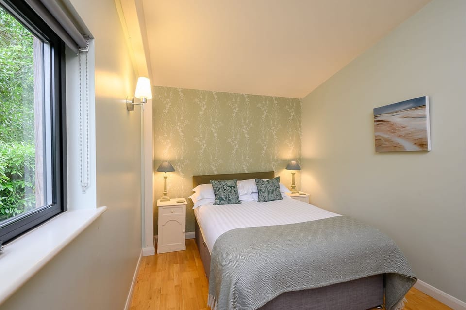 Bedroom in Jasper lodge with king-size bed, armchair and bedside lighting.