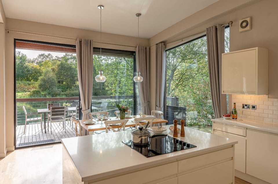 Modern kitchen with island, dining table and direct access to lakeside decking in Finley lodge.
