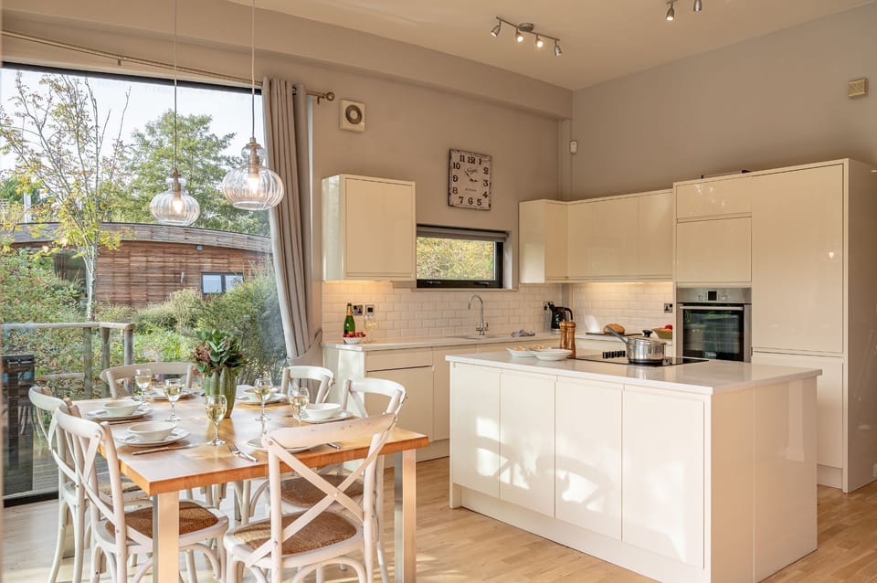 Modern kitchen with island, dining table and direct access to lakeside decking in Finley lodge.