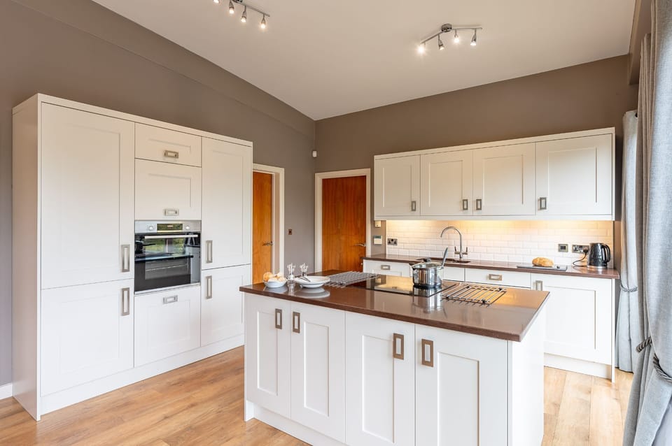 Modern kitchen at Willow, featuring a central island, built in oven and fully equipped appliances.