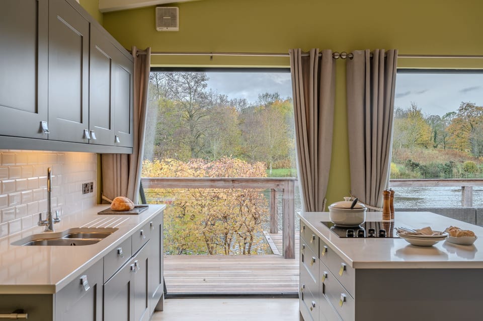 Modern, fully equipped kitchen In Louis lodge with island and grey cabinetry and lakeside views at Brompton Lakes.