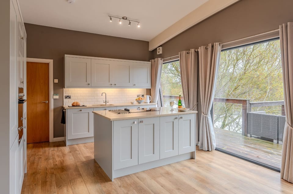 Modern open-plan kitchen in Flora lodge at Brompton Lakes with central island, integrated appliances and bright interiors.