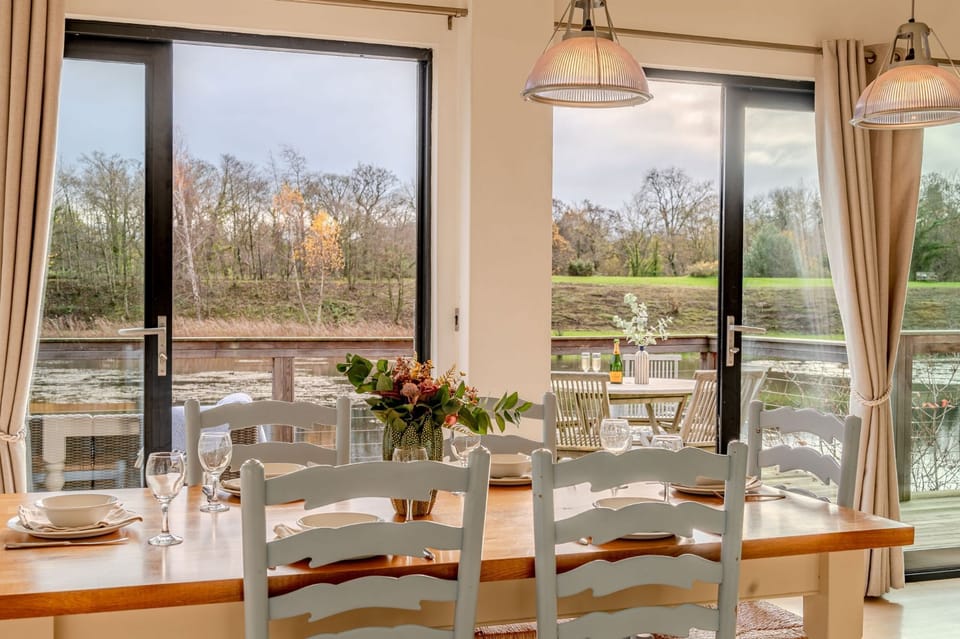 Dining area in Lulu lodge, Brompton Lakes with lakeside views through large windows.