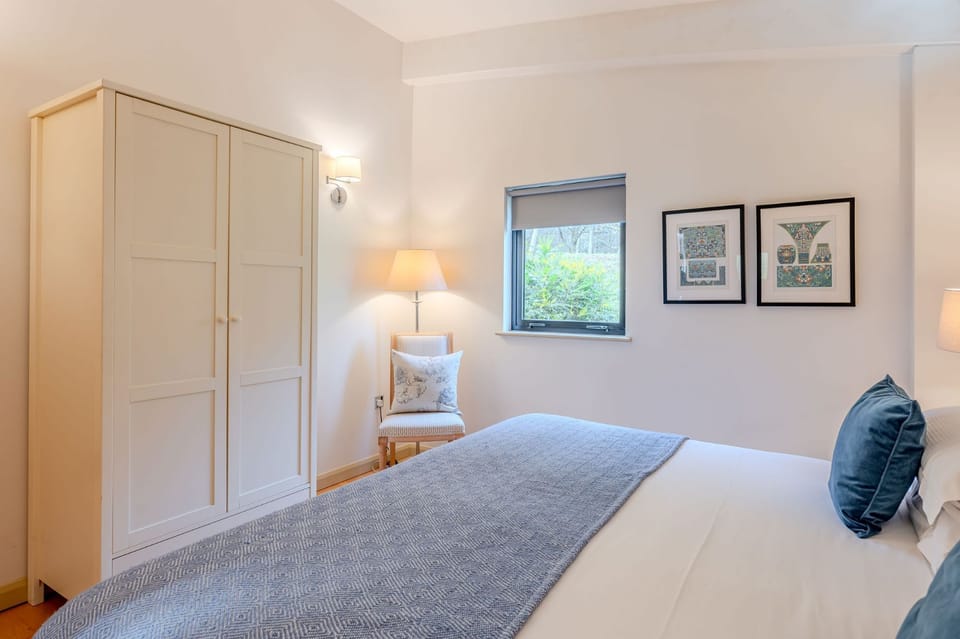 Double bedroom at Lulu lodge, Brompton Lakes with patterned feature wall, wardrobe, lamp and soft lighting.