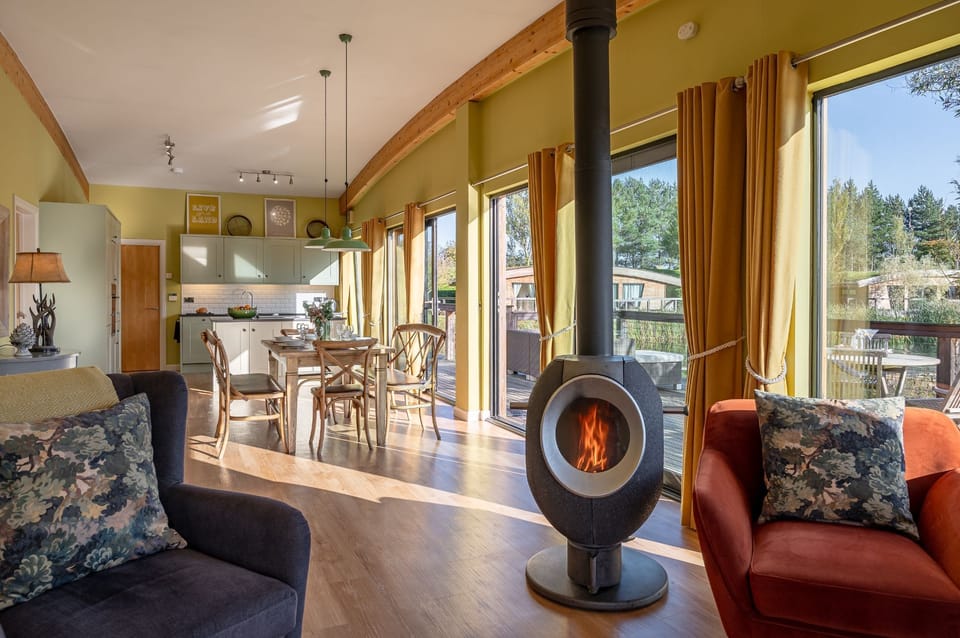 Open-plan kitchen, living  and dining area with floor-to-ceiling windows in Florence lodge at Brompton Lakes with lakeside views.