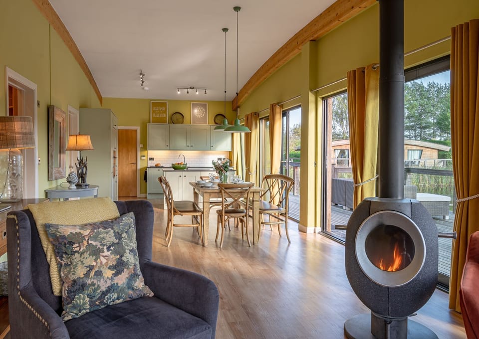 Open-plan kitchen, living  and dining area with floor-to-ceiling windows in Florence lodge at Brompton Lakes with lakeside views.