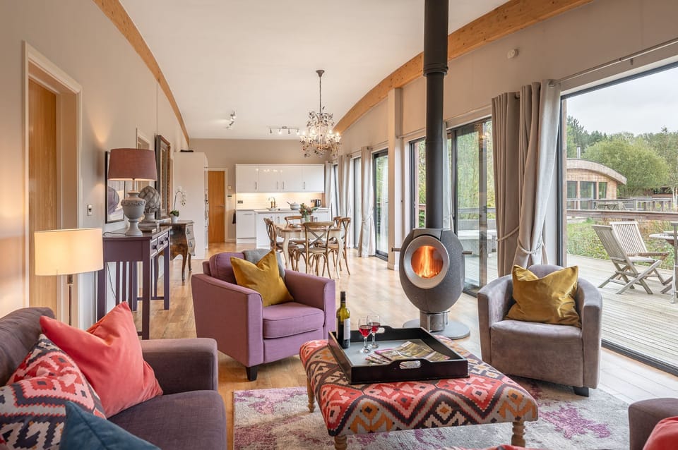 Open-plan living space in Charlie lodge at Brompton Lakes with wood-burning stove and lake views.
