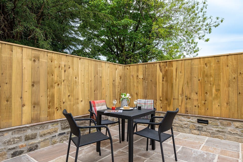 Private outdoor patio with table, seating and enclosed garden area in The Old Tack Room.