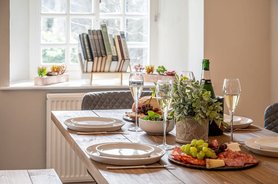 Close up of a beautifully set dining table in The Old Potting Shed with wine glasses, cheese board, fresh bread, and elegant tableware.