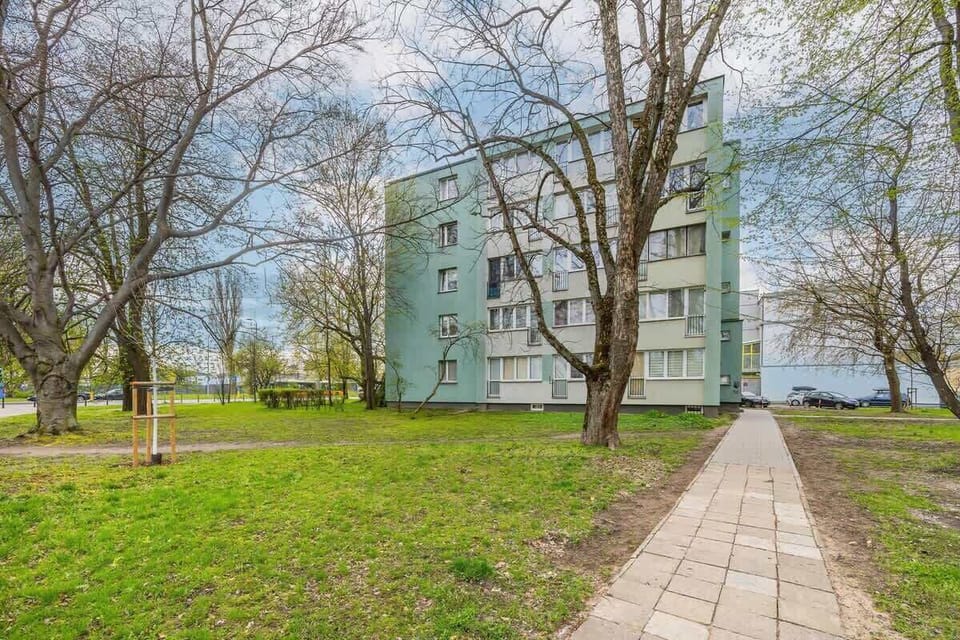 Entrance path and front view of the apartment building surrounded by trees.