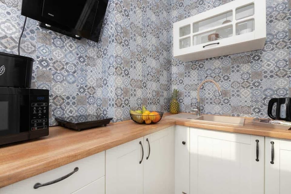 Small kitchen area with patterned tile backsplash, fruit bowl, and modern finishes.