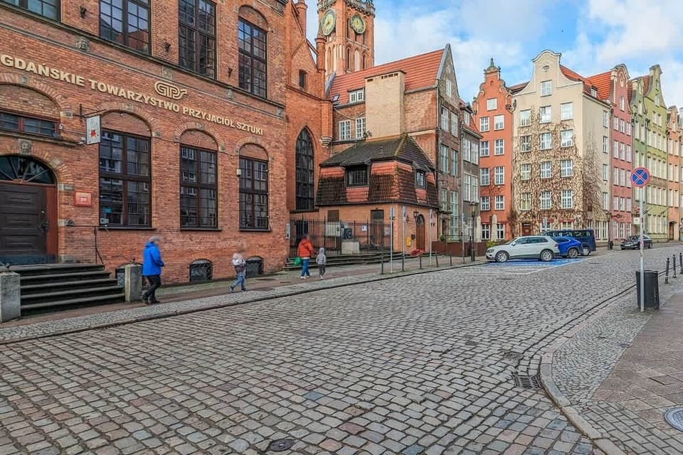Cobblestone street view with historic red-brick buildings, part of Gdańsk’s charming cityscape.