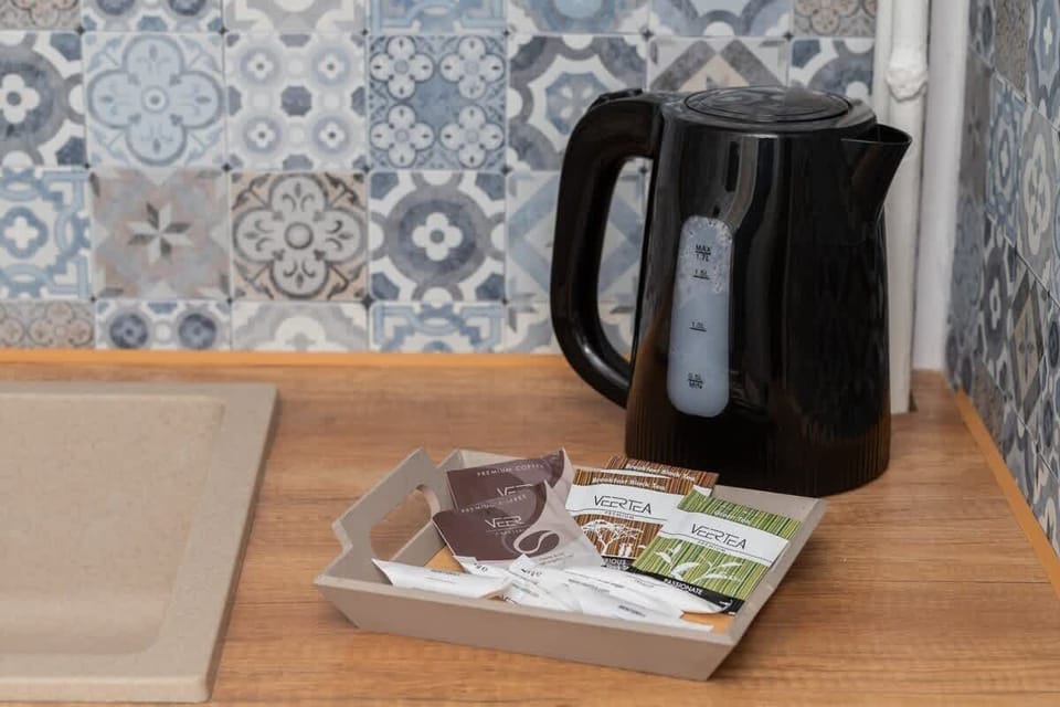Electric kettle on the kitchen counter with mugs and instant coffee/tea set.