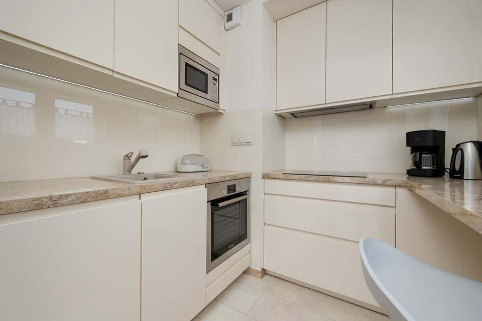 White modern kitchen with built-in appliances and a small table.