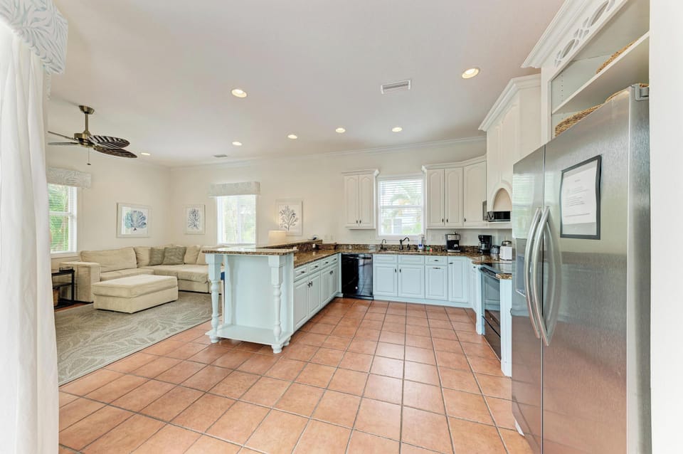 Your open-concept space blends a fully equipped kitchen with stainless steel appliances, granite countertops, and a charming island, plus a cozy living area with plush sectional seating—perfect for gathering, cooking, and unwinding together.
