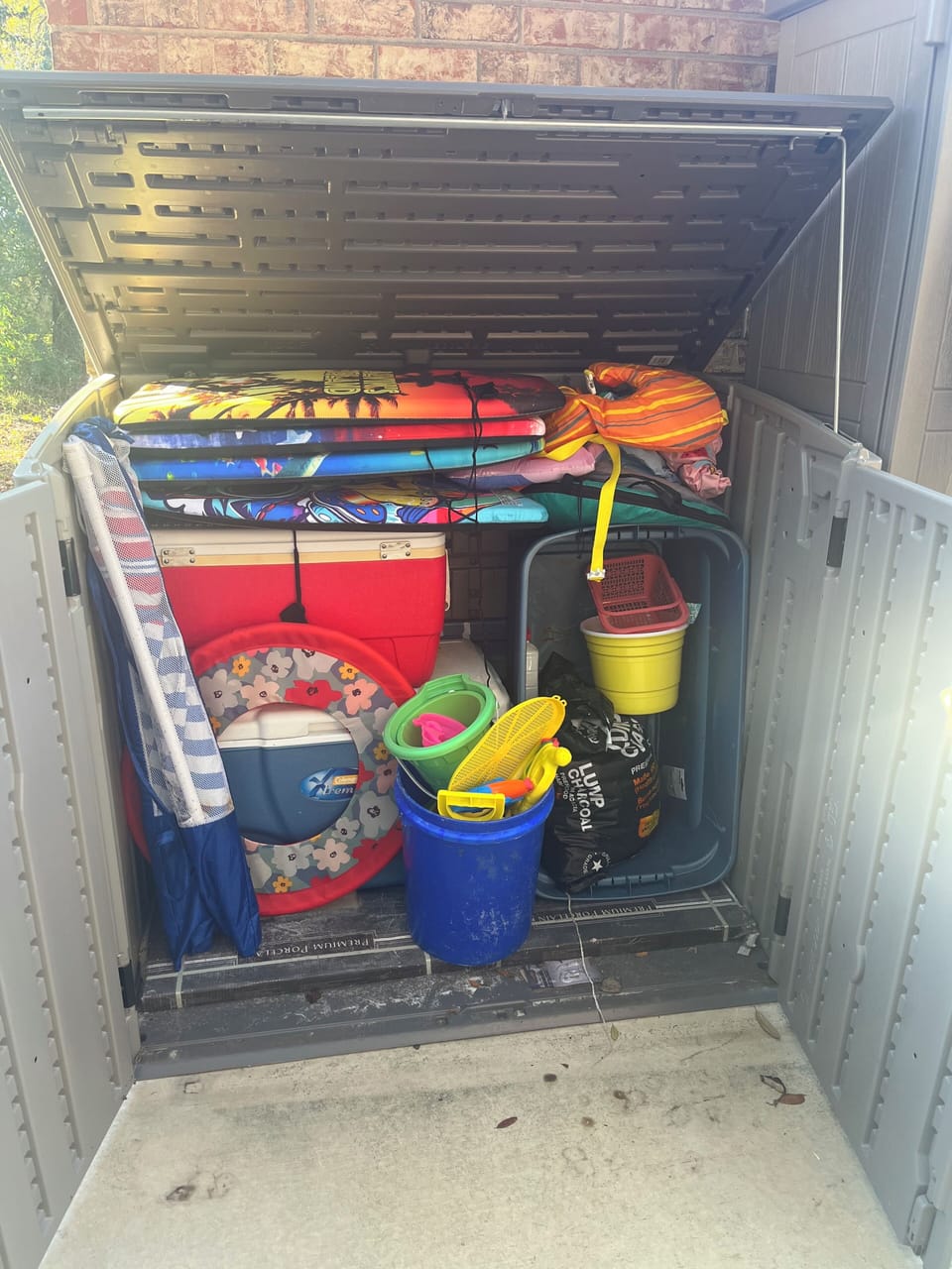 Outdoor storage bin has coolers, umbrellas, boogie boards, sand toys, frisbees!