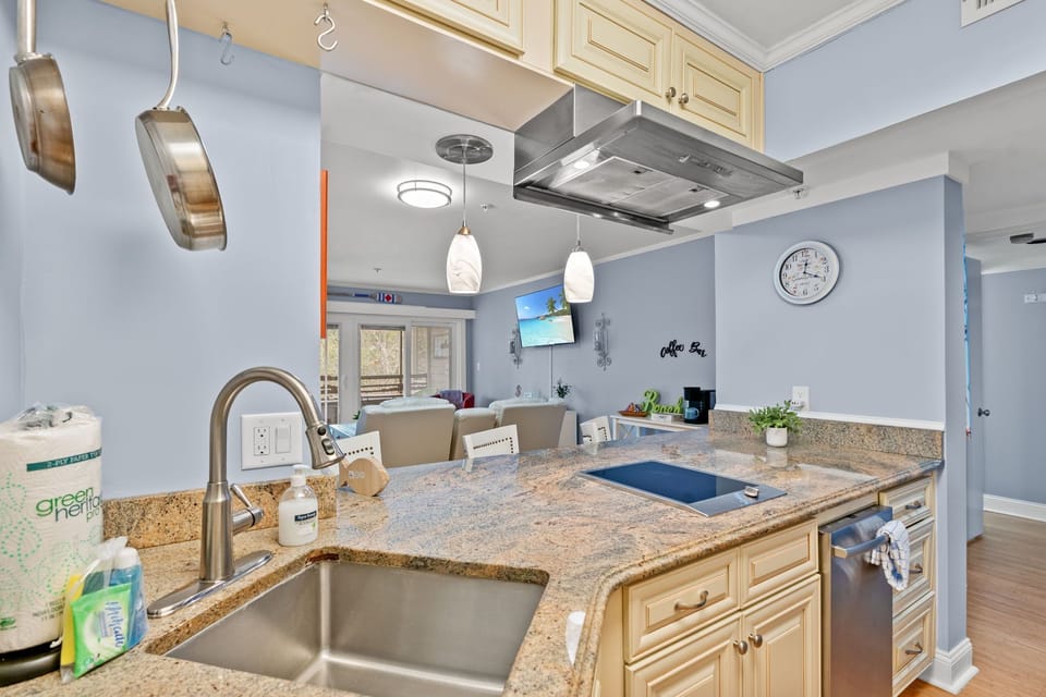 Granite kitchen with island seating, induction cooktop, and open living view
