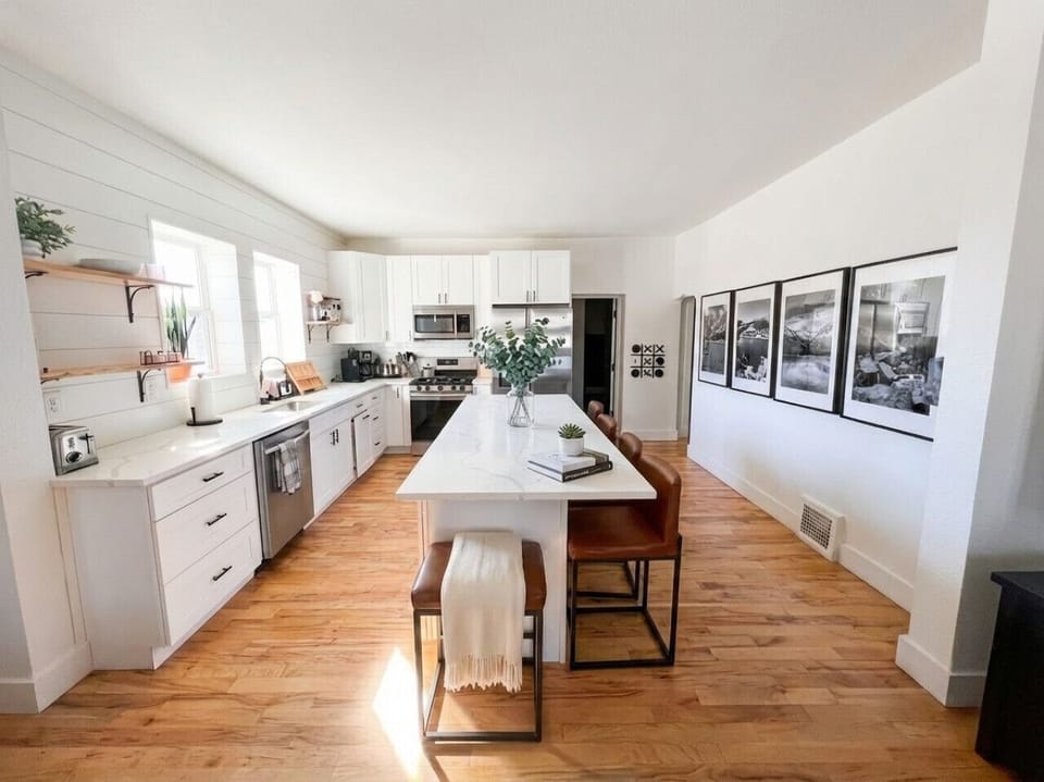 Chef`s kitchen with quartz island, leather bar seating, and shiplap accent wall -- fully equipped for cooking