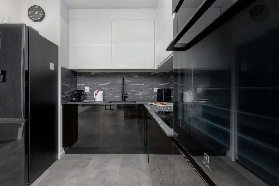 A contemporary kitchen with glossy black cabinetry, built-in appliances, and minimalist details.