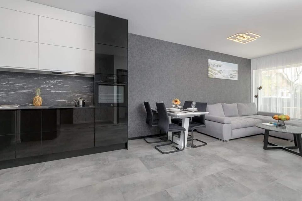 A modern open-plan living and dining area with a grey corner sofa and a stylish table set for four.