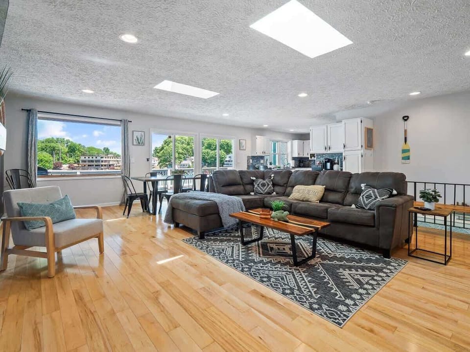 Bright living room w/ large windows, cozy seating & TV for relaxed evenings indoors