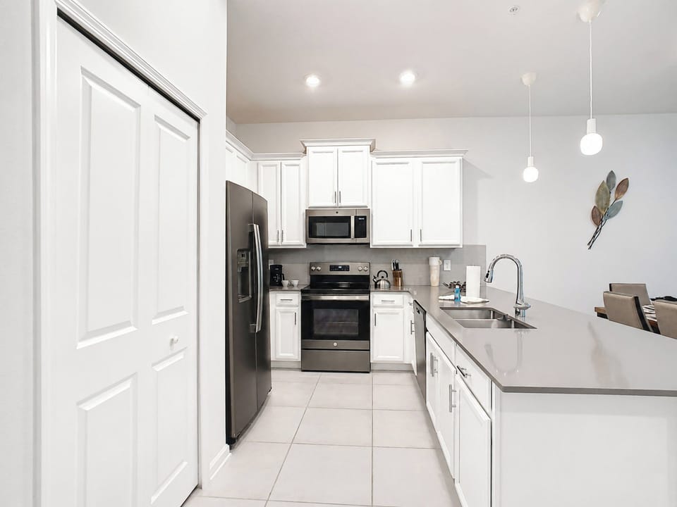 Fully equipped kitchen with white cabinets and modern appliances