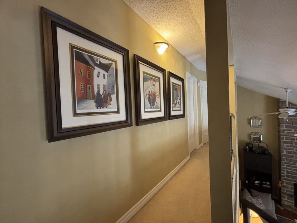 Hallway Gallery: Stroll through the upstairs hallway of The Louise, lined with framed art that adds a cultural touch to the space. These prints provide guests with visual stories, creating a personal gallery experience as they move between the cozy comforts of the cottage's rooms.
