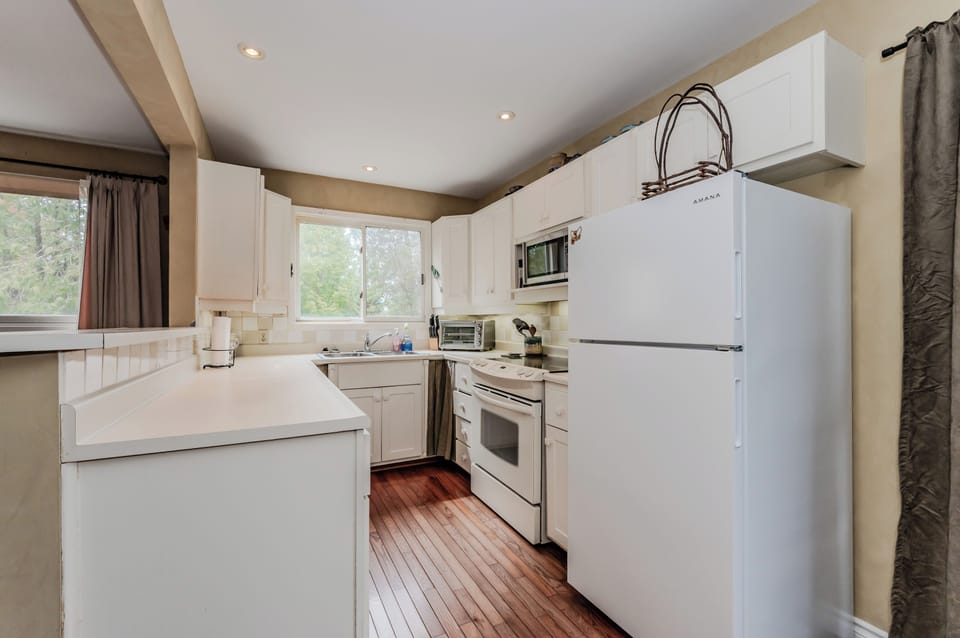Bright and functional kitchen equipped with essential appliances, cookware, and plenty of space for preparing cottage meals.