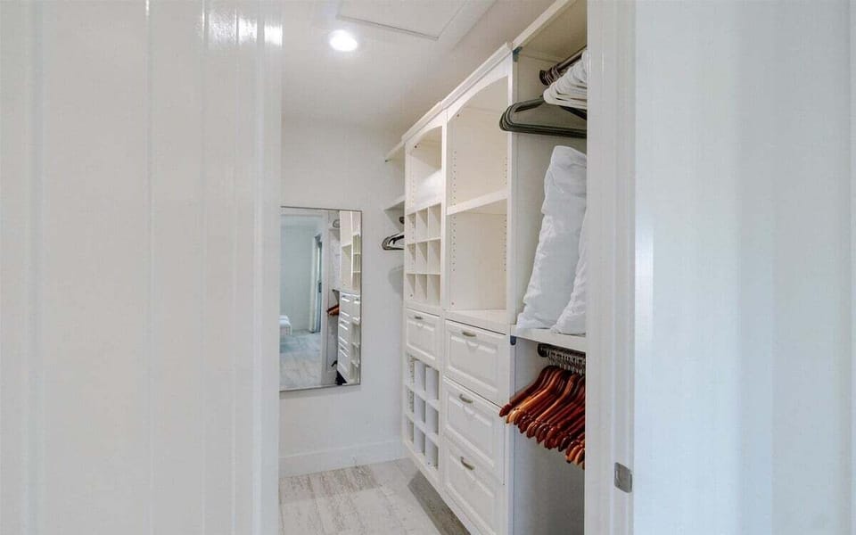 Spacious walk-in closet with custom shelving and ample storage for clothing and luggage.