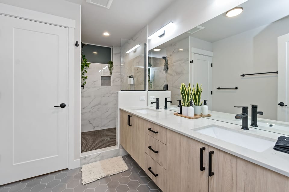 Hotel-grade luxury: marble-look tiles, black hardware, dual sinks & glass shower
