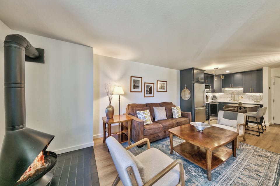 Cozy up by the fireplace in your open-plan retreat, where modern kitchen meets comfortable living space with warm wood tones.