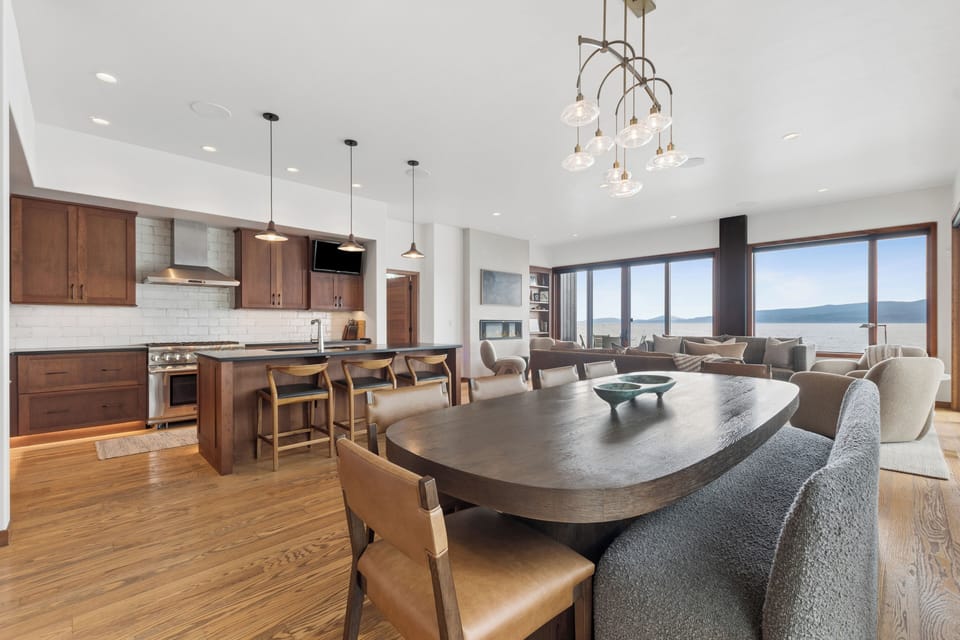 Step into your open-concept living space where warm wood tones meet modern elegance. Gather around the expansive dining table, cook in your fully-equipped kitchen, and soak in breathtaking lake and mountain views through floor-to-ceiling windows.