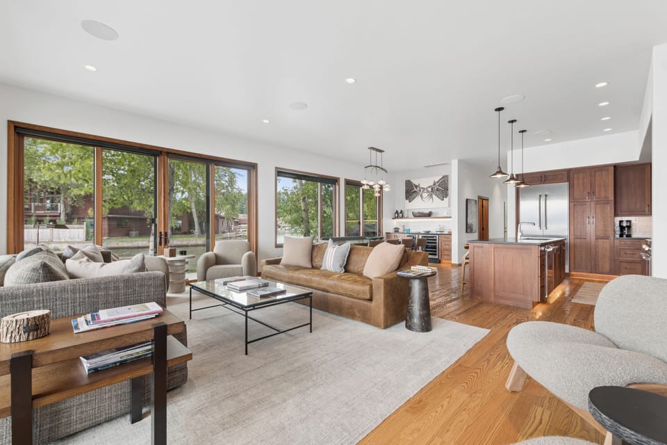 Sunlight streams through expansive windows into the open-concept living space, where warm wood tones and modern design create an inviting atmosphere perfect for relaxing or entertaining.
