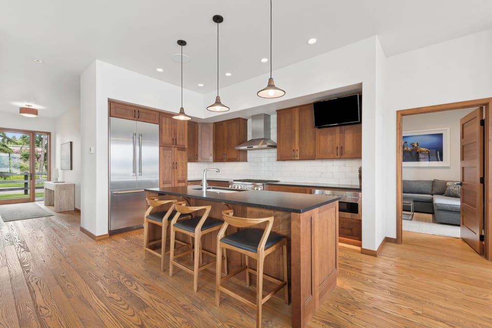 Step into your beautifully appointed kitchen, where warm wood cabinetry and sleek modern appliances create the perfect space for preparing meals and gathering with loved ones around the stylish island.