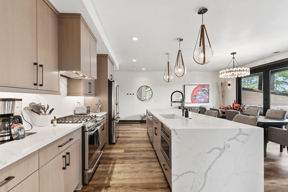 Gather around this bright, open kitchen where gleaming marble counters and modern fixtures set the stage for your culinary adventures. Natural light pours in, making every meal feel like a special occasion.