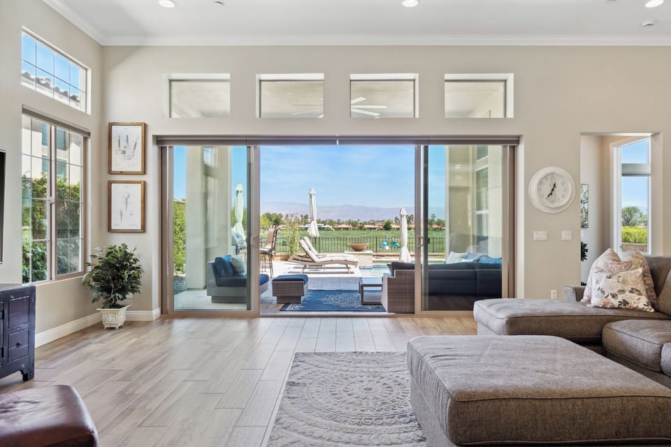 Floor-to-ceiling glass opens to pool and patio.