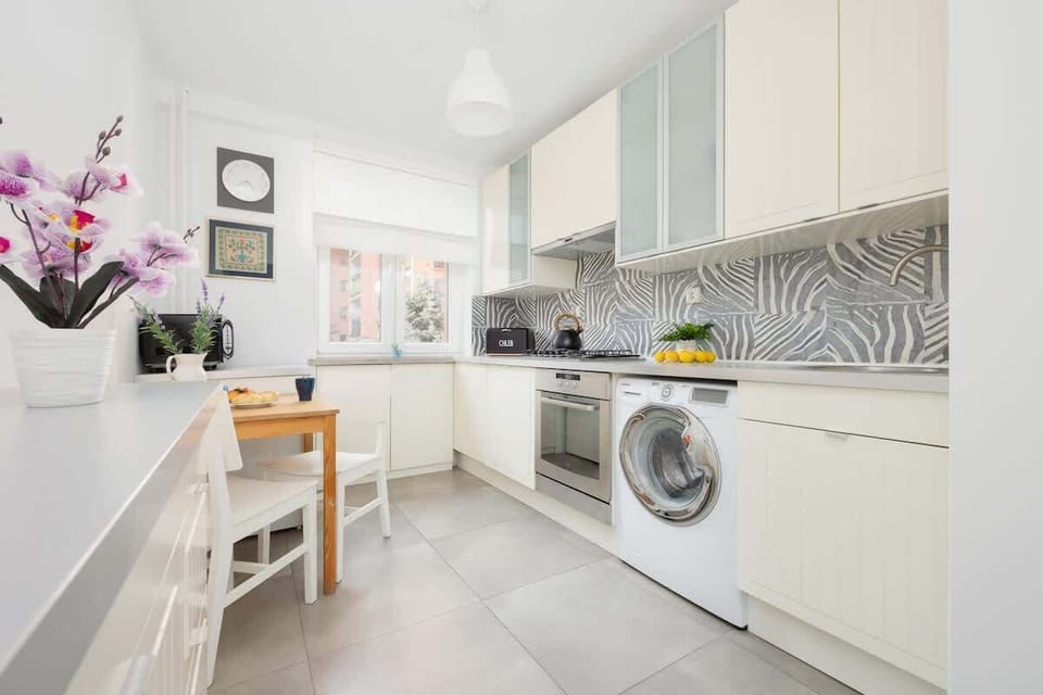 Kitchen with white cabinets, washing machine, and tiled backsplash.