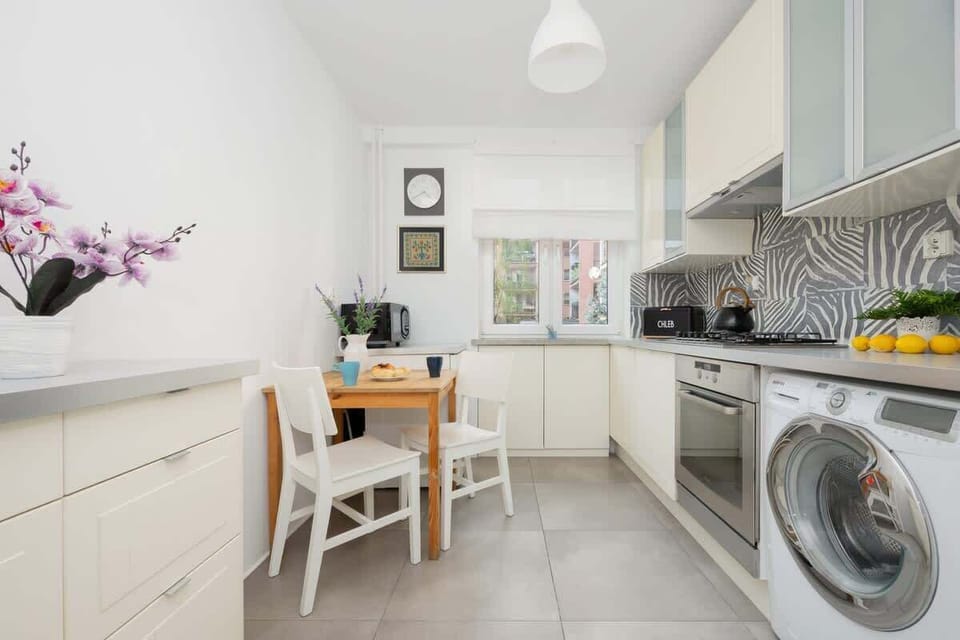 Kitchen with white cabinets, washing machine, and tiled backsplash.