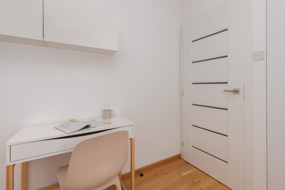 A second view of a workspace, highlighting the desk’s neat design and a cozy corner setup within the bedroom.