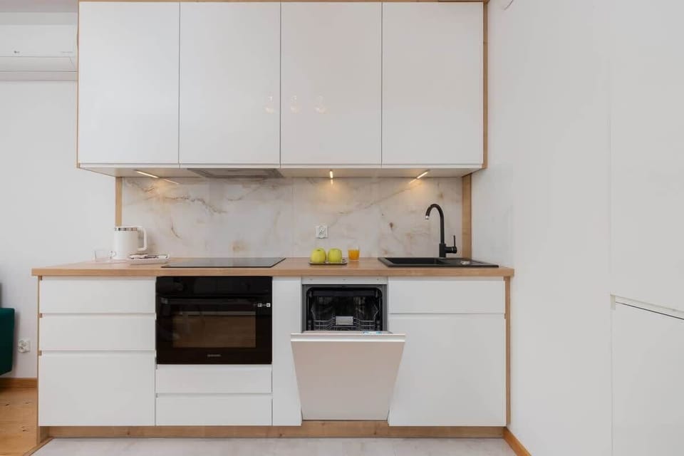 A close-up of green decor items on the kitchen counter, adding a fresh touch to the modern, white kitchen.