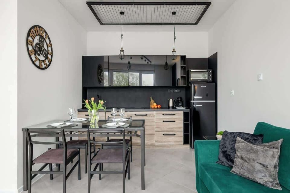 A functional kitchenette with wooden cabinets, black countertops, and all the essentials for cooking.