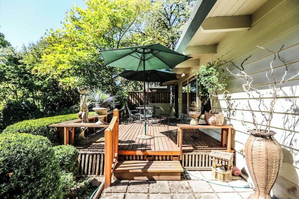 Private backyard retreat with a spacious deck, shaded umbrella, and lush greenery — ideal for morning coffee, outdoor dining, or celebrating with friends after a Ducks game at Autzen Stadium.