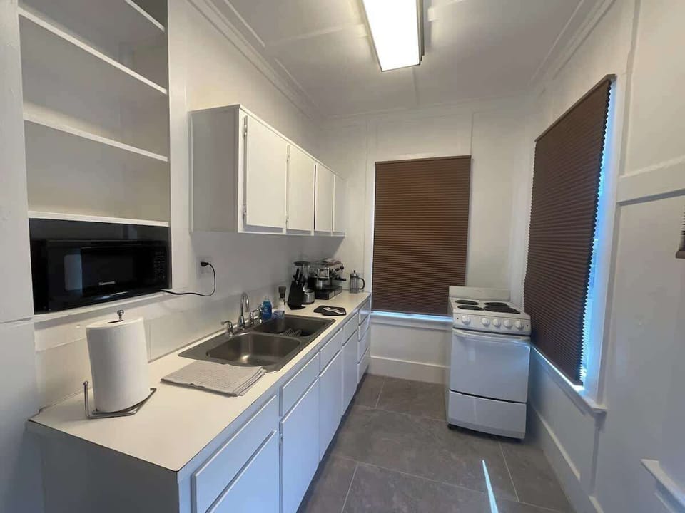 Kitchen with stove, oven, microwave, hot water heater, air fryer, coffee maker, dishes, utensils, spices, and more kitchen essentials.