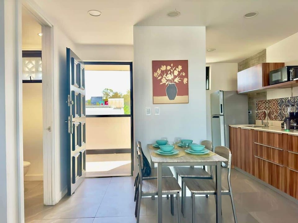 La fotografía muestra la vista desde la sala hacia la entrada principal. 
Tenemos en este espacio un pequeño comedor con servicio para cuatro personas, cocina completamente equipada para la renta vacacional, el cuarto de lavadora y medio baño .