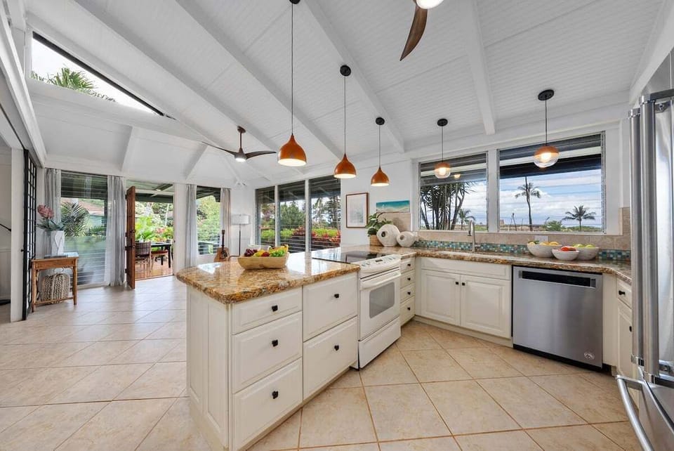 Cook and entertain in a spacious kitchen with a large island, modern appliances, and panoramic windows framing tropical scenery