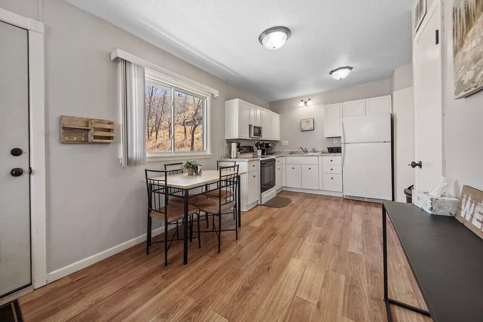 A modern kitchen seamlessly integrated with a dining area featuring a sleek table, designed to comfortably accommodate four guests for intimate meals and conversations.
