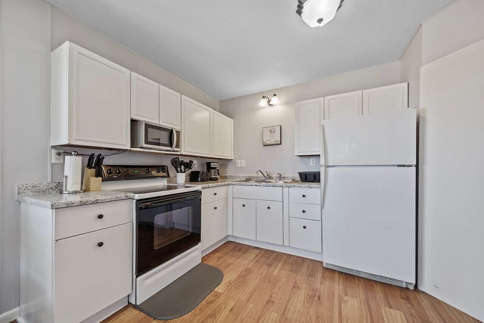 A well-appointed kitchen featuring modern amenities such as a dishwasher, refrigerator, and microwave, all fully stocked to meet your culinary needs with ease and convenience.