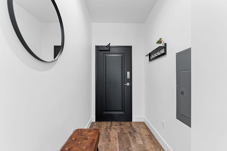 Step into your stylish entrance with warm wood floors, a sleek round mirror, and thoughtful hooks for your belongings.